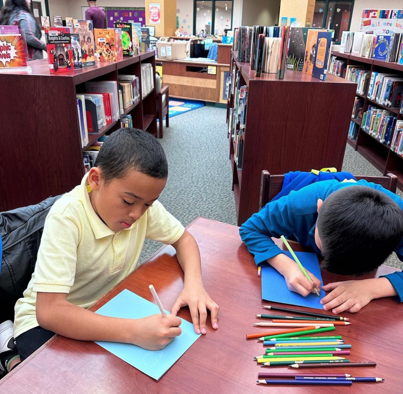 Two elementary students writing at a table during a Learn Like Me session